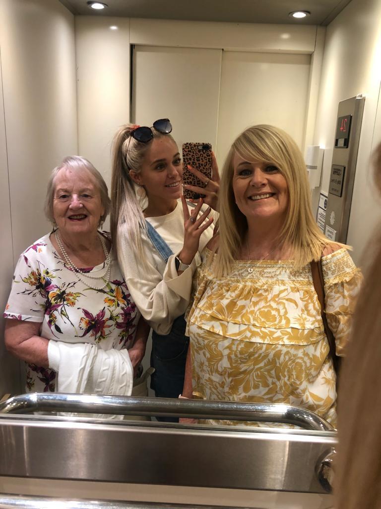 Three woman smiling in a lift mirror