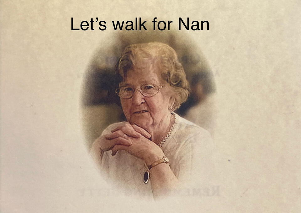 An older woman with light brown hair, glasses and a white top with the text Let's walk for Nan at the top