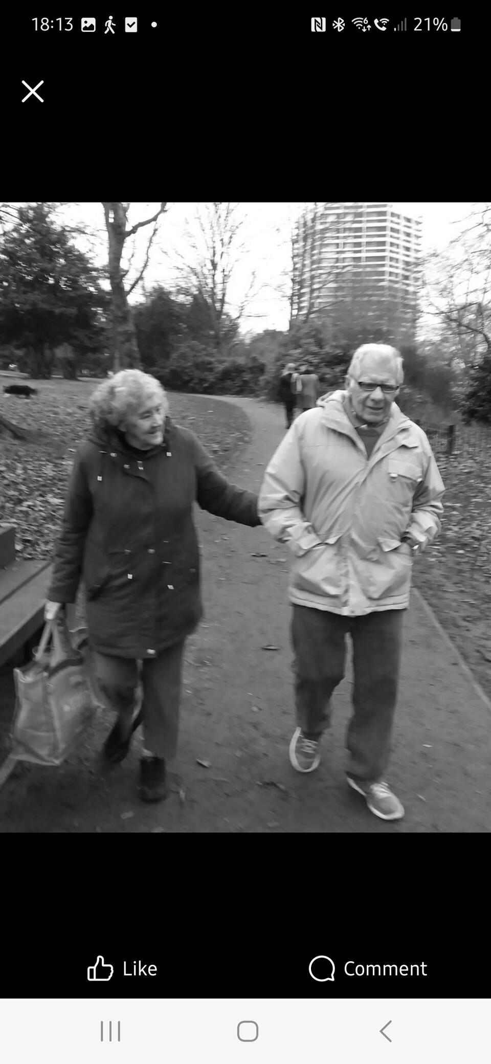 A black and white photo of a woman and man walking in a park