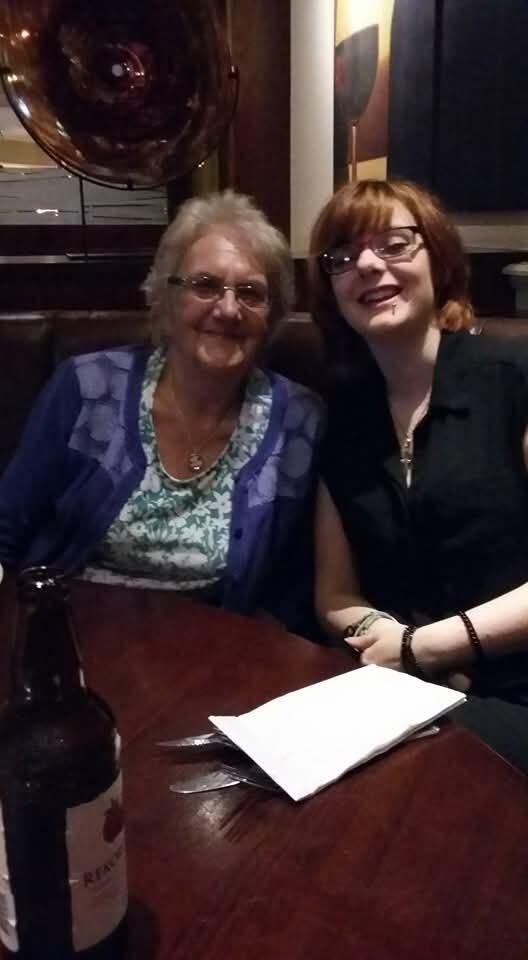 An older later with short grey hair and glasses sat with a younger woman with a ginger bob and glasses. Both are in a pub and smiling