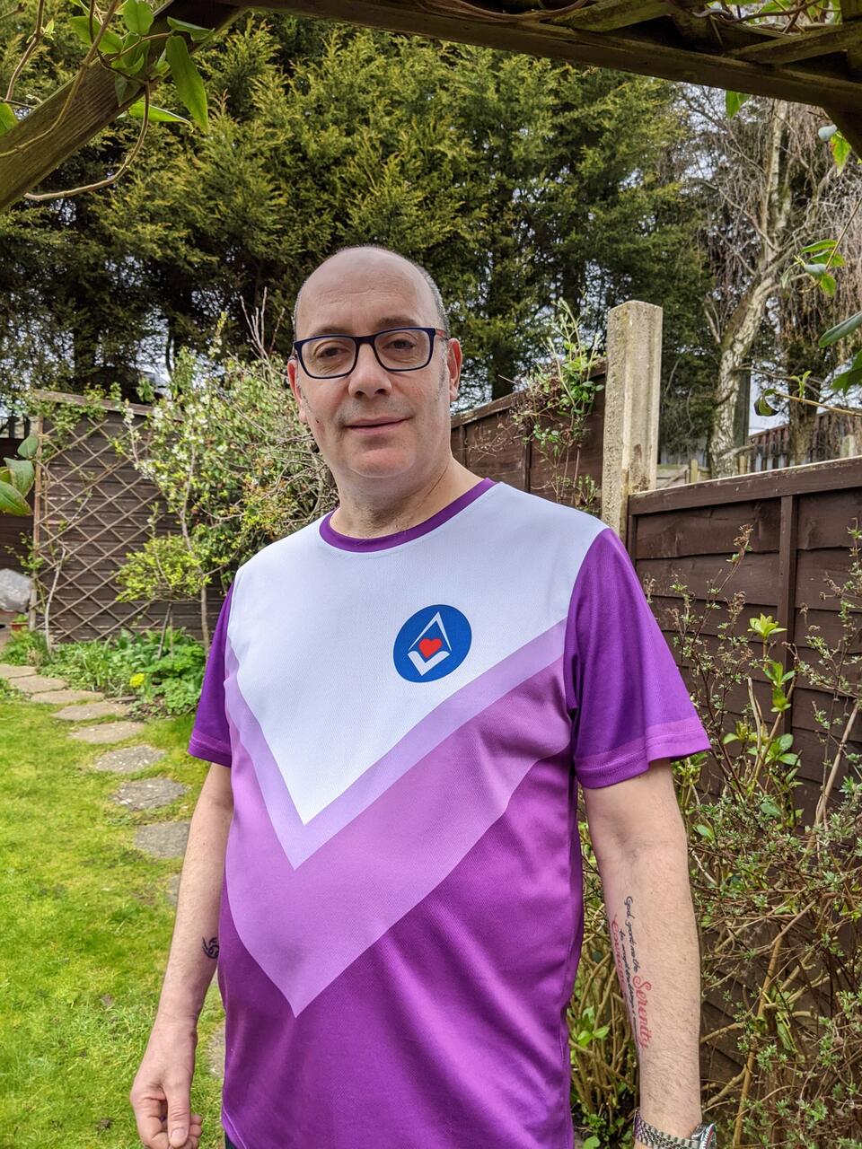 A bald man wearing glasses and a white and purple running top