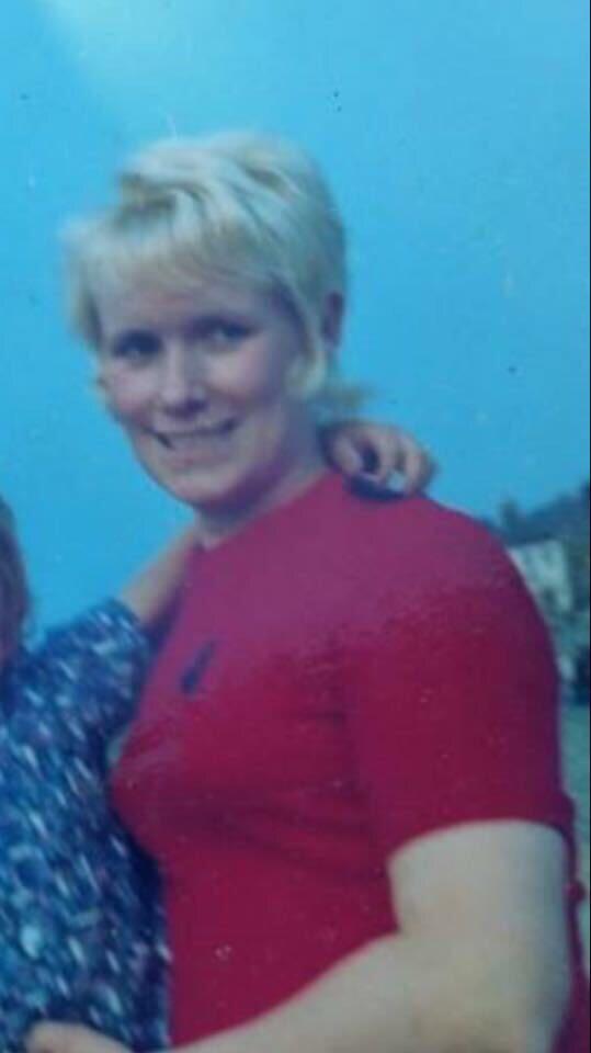 A woman with short blonde hair and a pink t-shirt