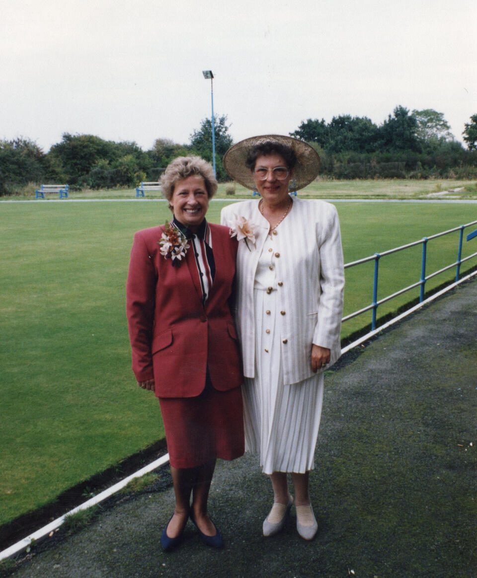 A woman with short blonde hair wearing a red suit stood next to another woman with a brown hair and white suit