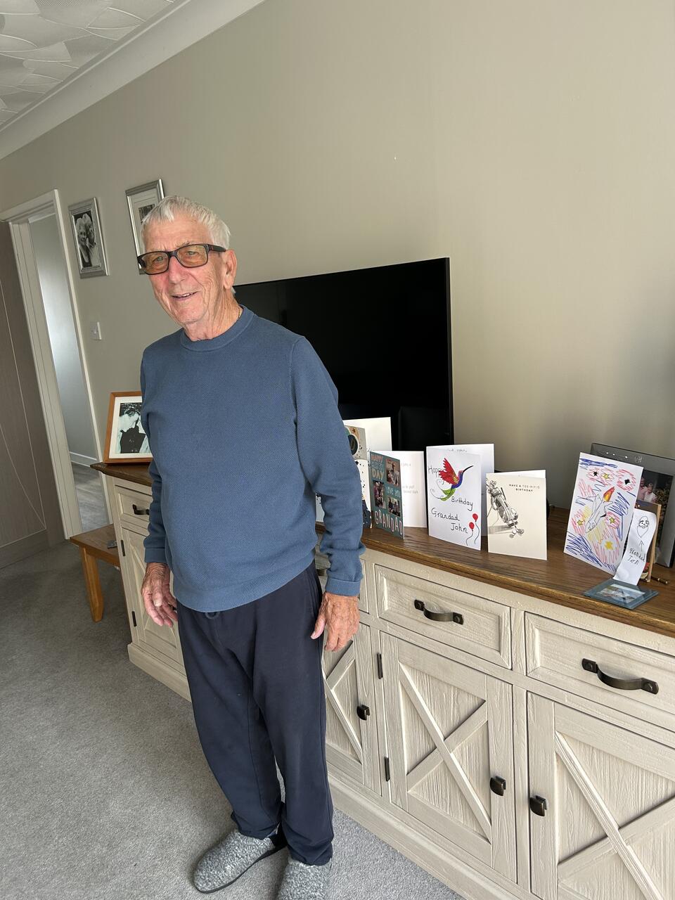 A man stood in front of a sideboard with cards on top