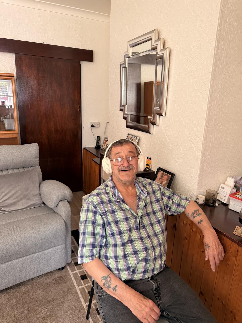 A smiling man wearing headphones sat in a chair