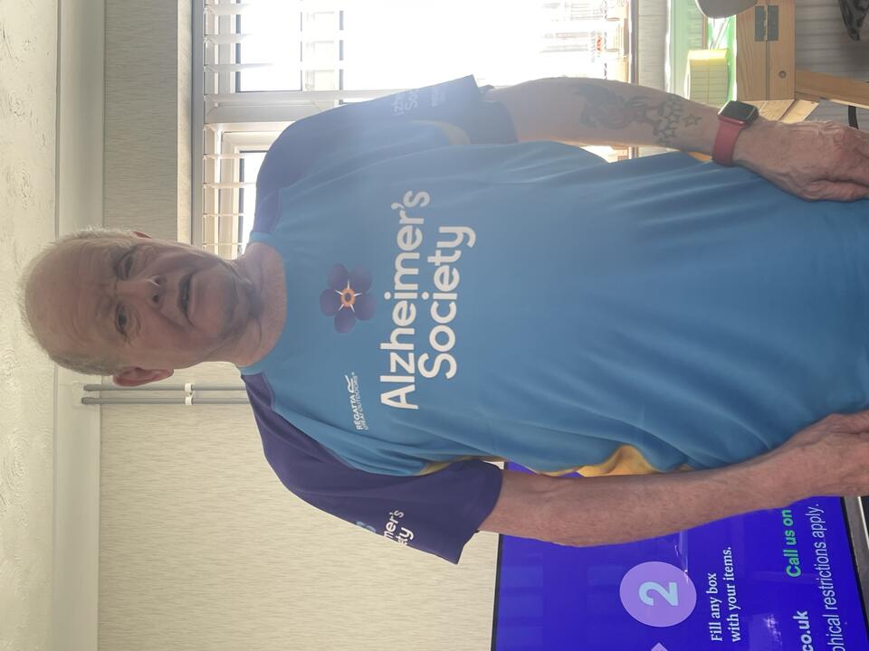A bald man wearing a blue Alzheimer's Society top 