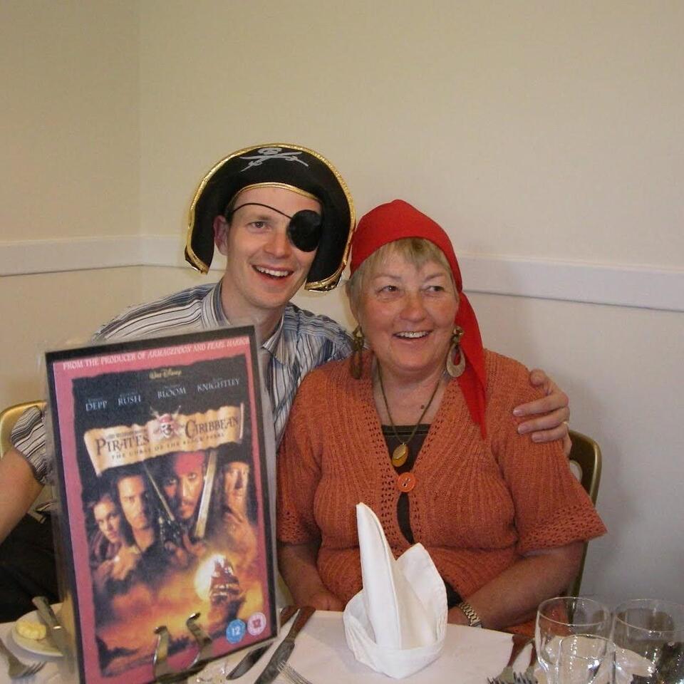 A man and woman dressed as pirates, smiling and hugging