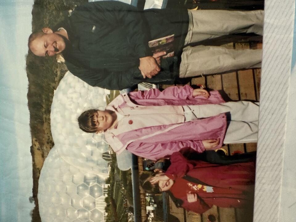 A film photo of a man, older girl and younger girl at the Eden Project. Two large domes are in the background