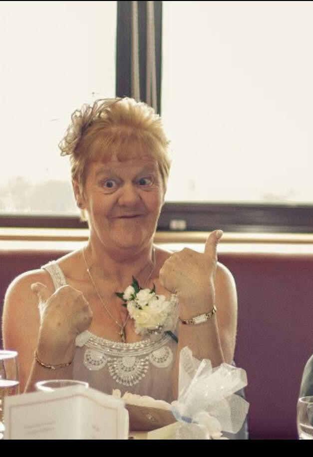 A woman with short blonde hair smiling with her thumbs up