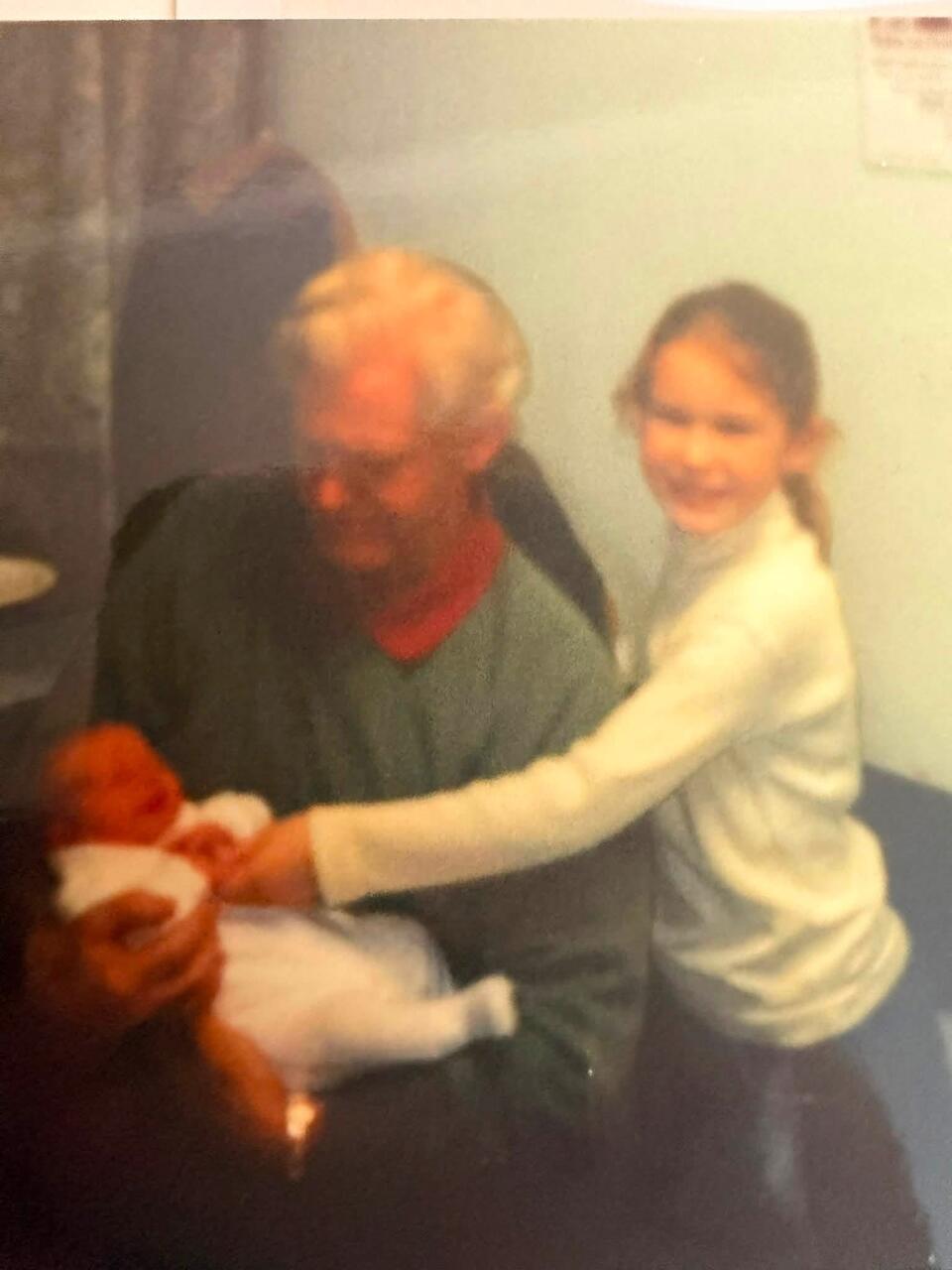 A man holding a baby and a girl holding the baby's hand