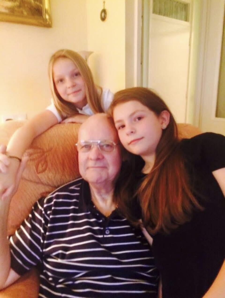 Two girls sat on a chair with a man