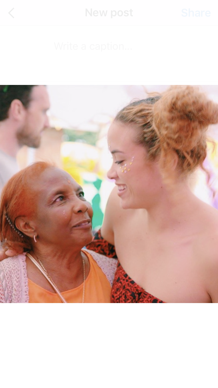 An older lady with a headwrap looking up at a younger woman with blonde curly hair