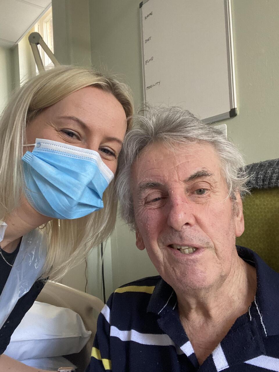 A woman with blonde hair and wearing a blue mask with an older man with grey hair and a blue stripy t shirt