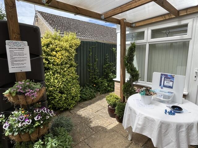 A table with a sign on the patio of a garden