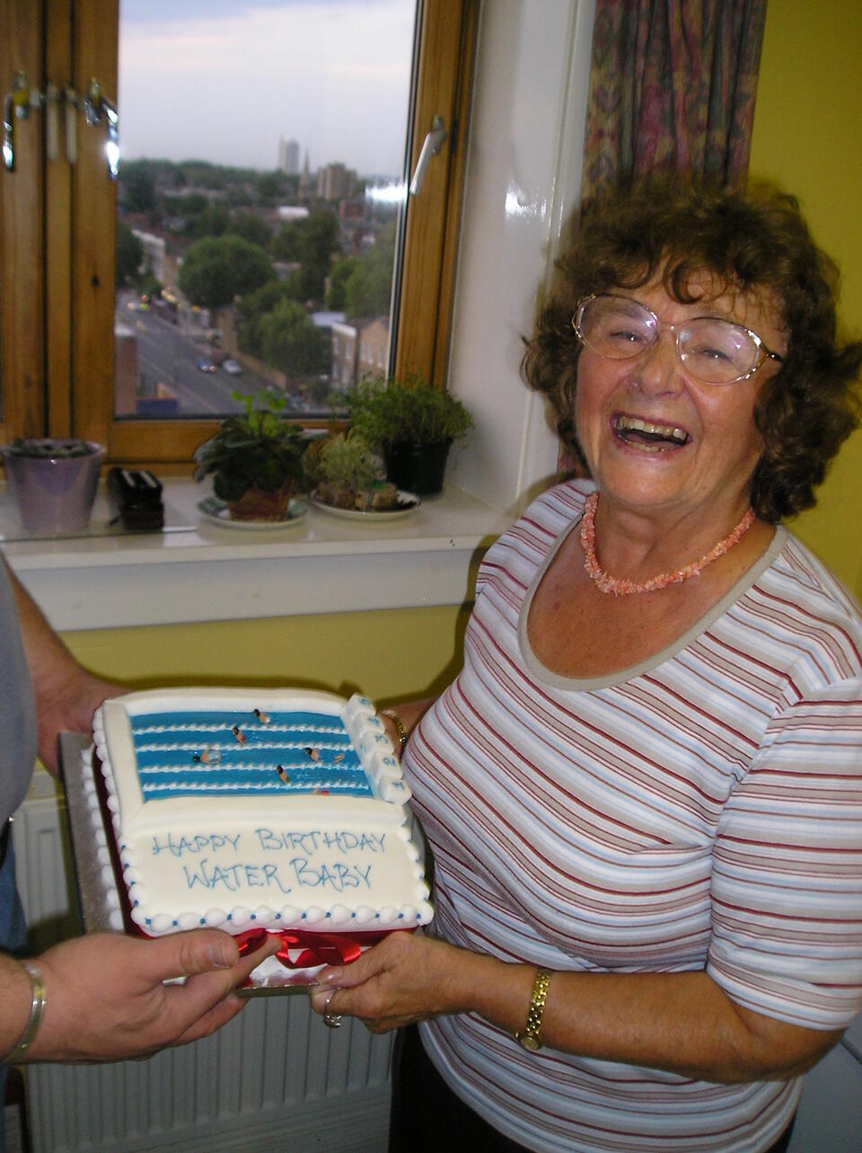 A woman in a stripy top smiling while holding a cake