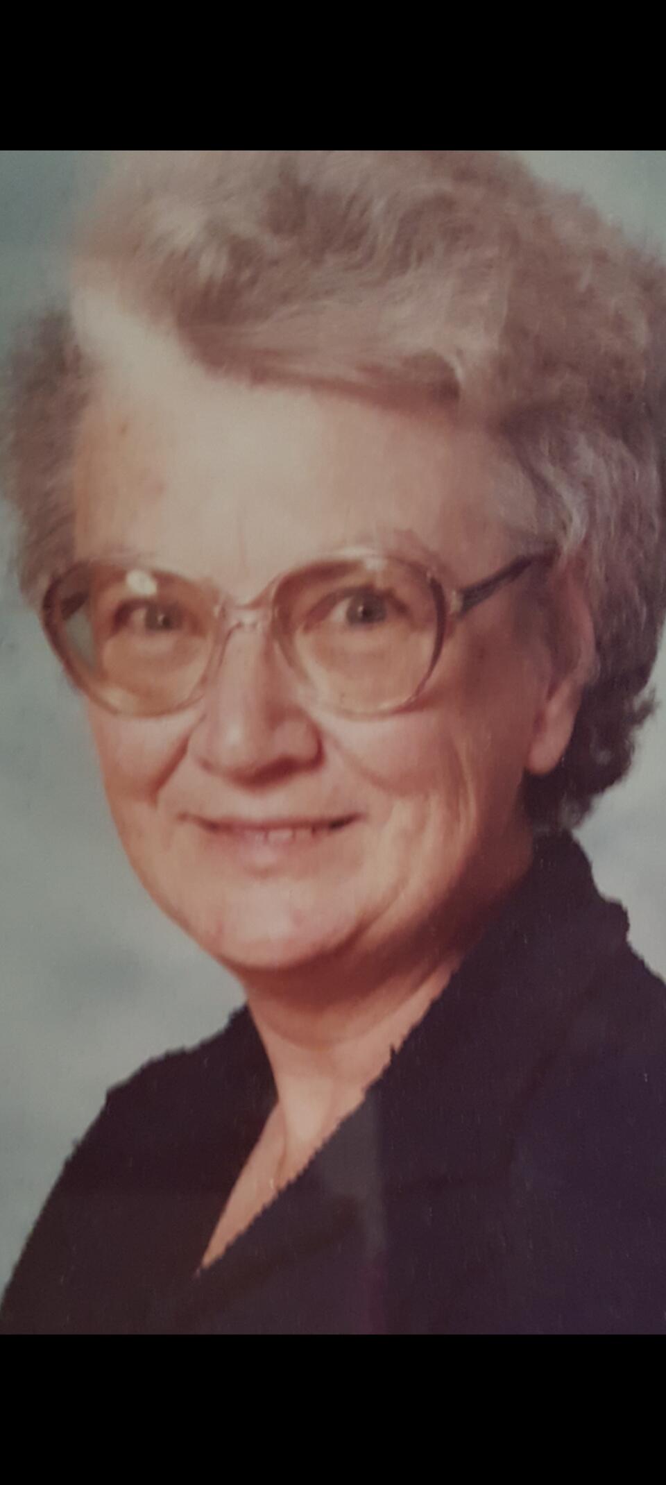 A woman with grey hair and brown tinted glasses