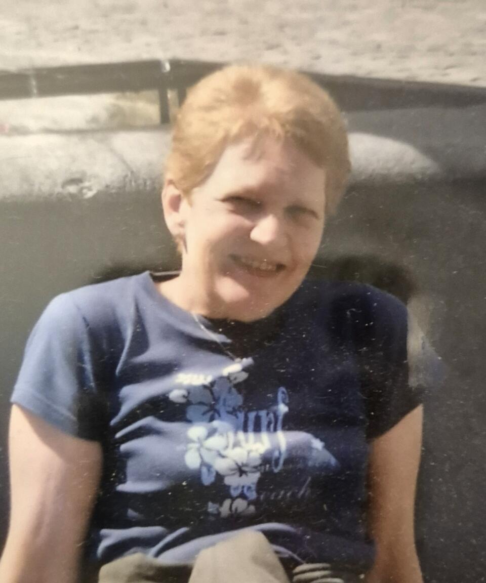 A woman with short blonde hair wearing a patterned blue t-shirt