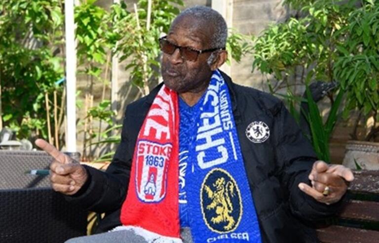 Raymond James sitting in a garden in his Chelsea scarf