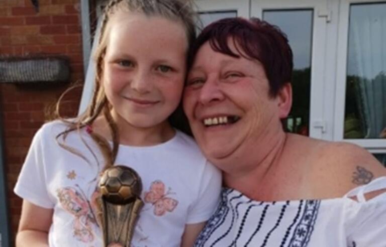 Amanda Griffiths with her granddaughter holding a football trophy