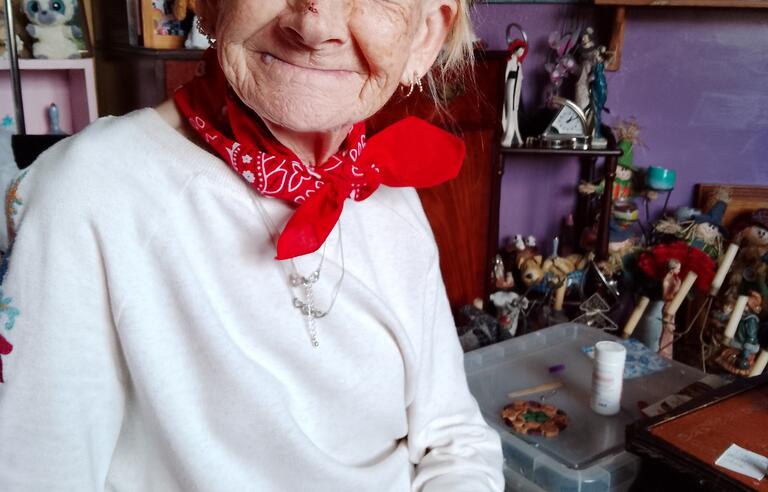 A woman wearing a grey cap, red scarf and white top