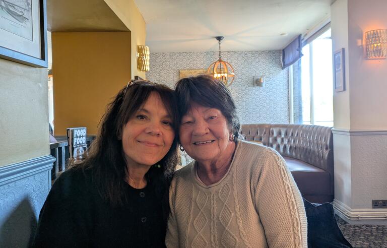 Two women with short brown hair, the woman on the left wearing a dark shirt and the woman on the right wearing a cream jumper