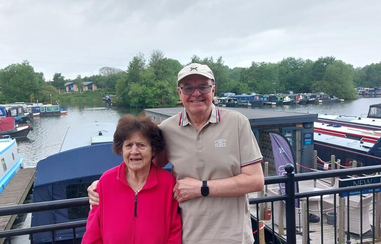A man with his arm around a woman on a bridge above a river