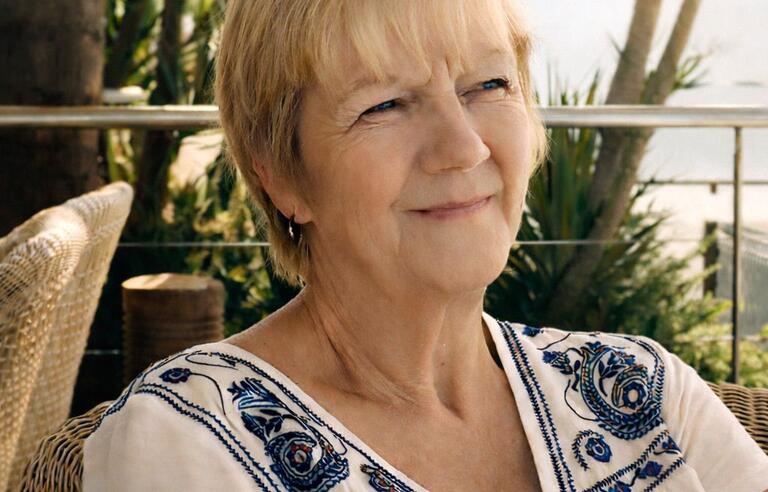 A woman with short blonde hair and white patterned top