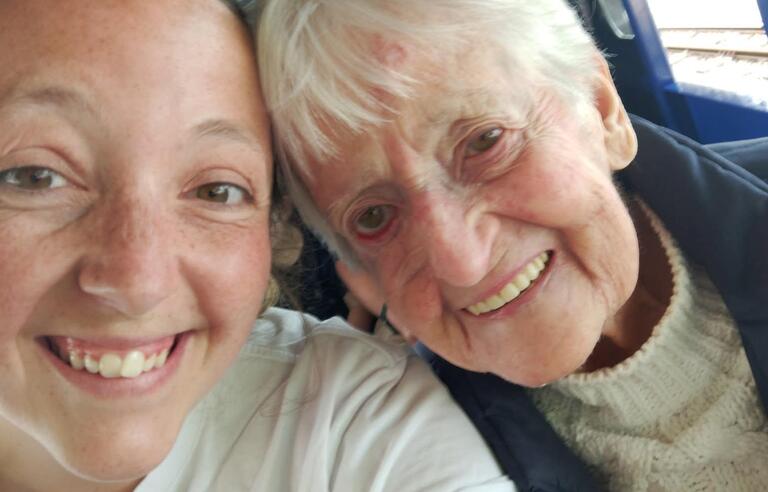 A younger woman taking a selfie with an older woman