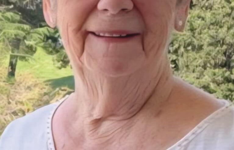 A woman with short white hair wearing a white top