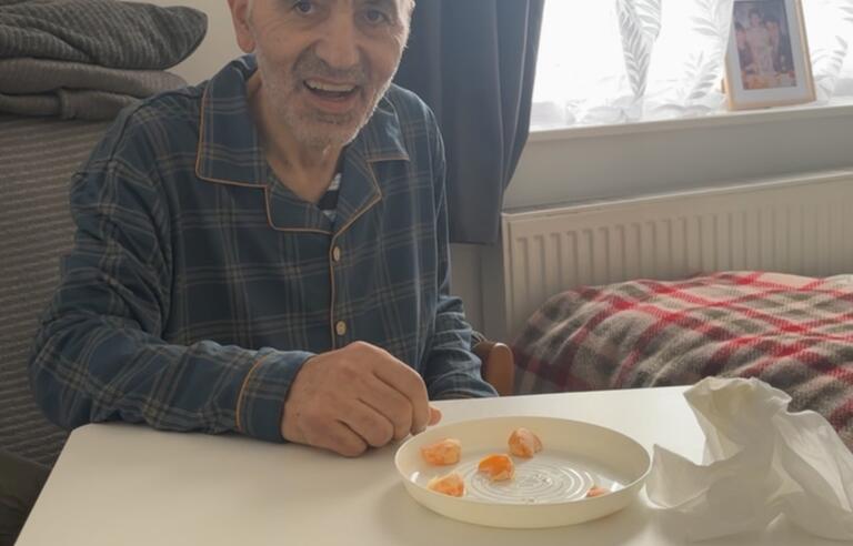 A bald man in a dark check shirt sat at a white table