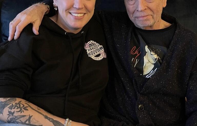 A man sat with a woman with his arm around her shoulders