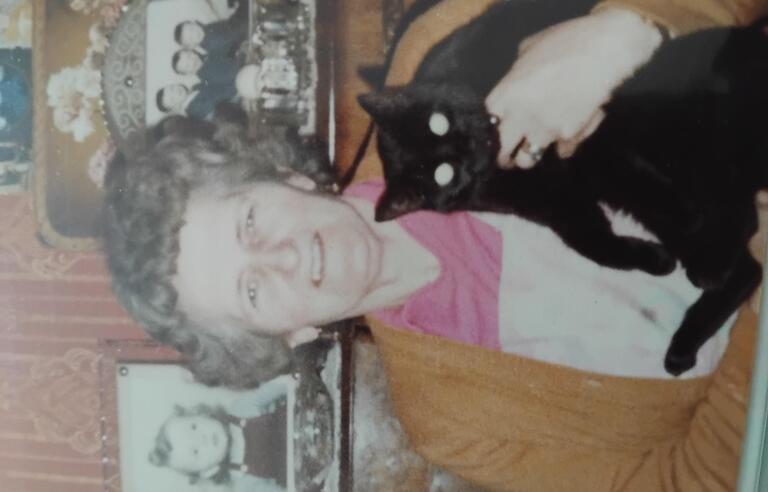 An older woman holding a black cat