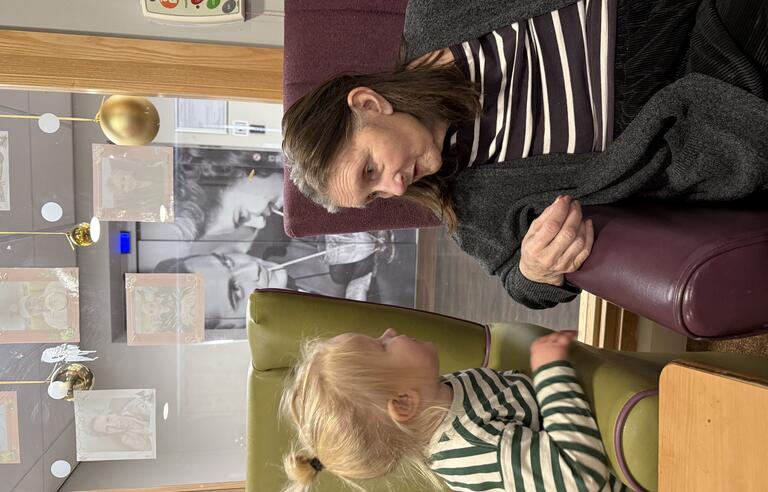 A young girl sat in an armchair talking to a woman in an armchair