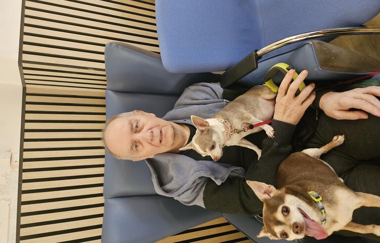 A man sat in a chair with two small dogs