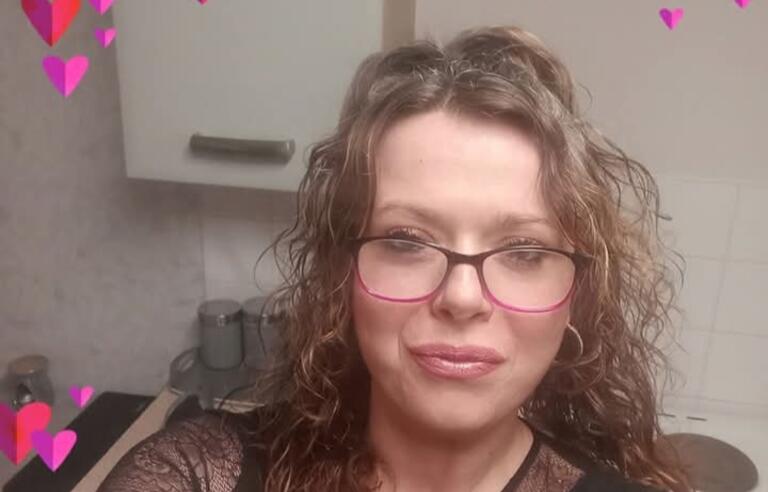 A lady wearing glasses taking a selfie surrounded by cartoon hearts
