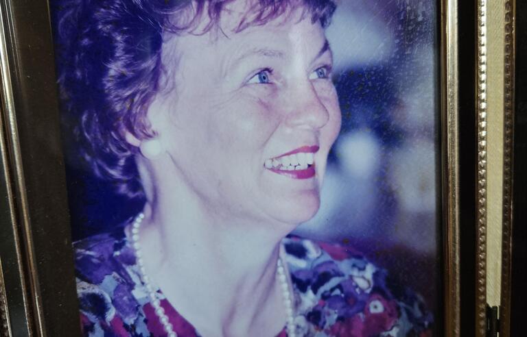 A woman with brown curly hair with red lipstick and a flowery dress