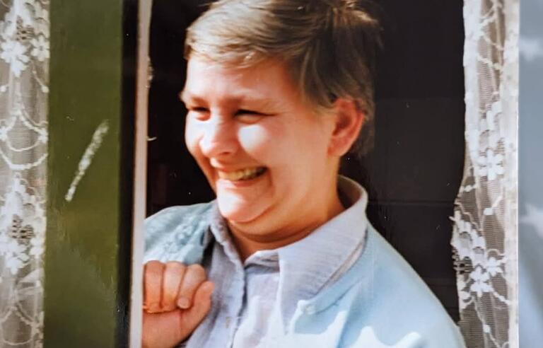 A woman with short dark hair wearing a light shirt and blue cardigan