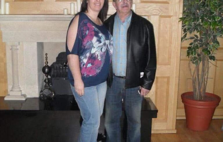 A woman with short brown hair and a man with glasses stood together and smiling