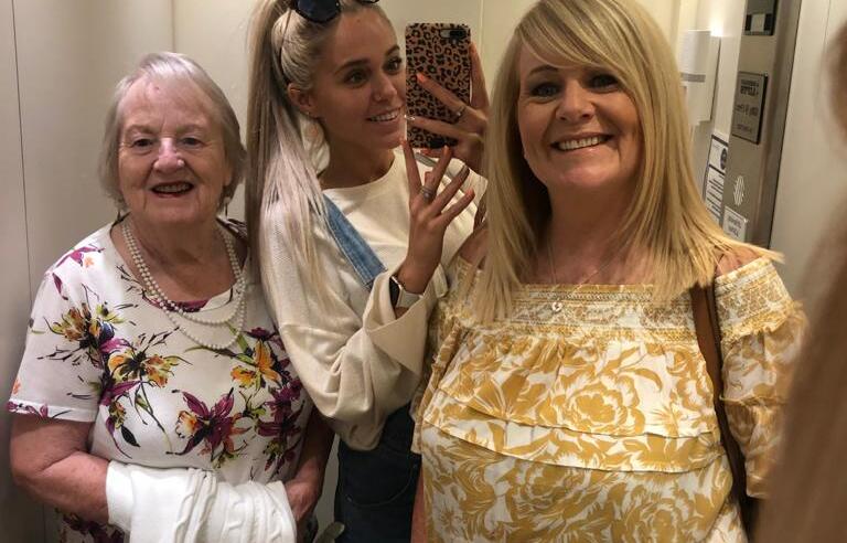 Three woman smiling in a lift mirror