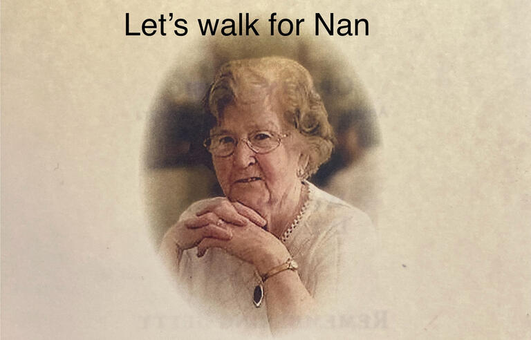 An older woman with light brown hair, glasses and a white top with the text Let's walk for Nan at the top
