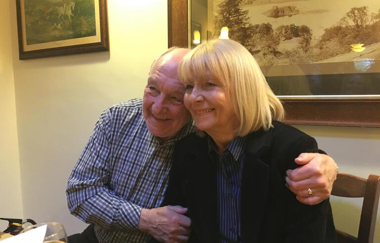 A man hugging a woman at a table