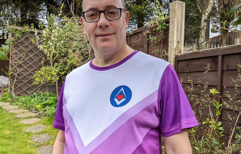 A bald man wearing glasses and a white and purple running top