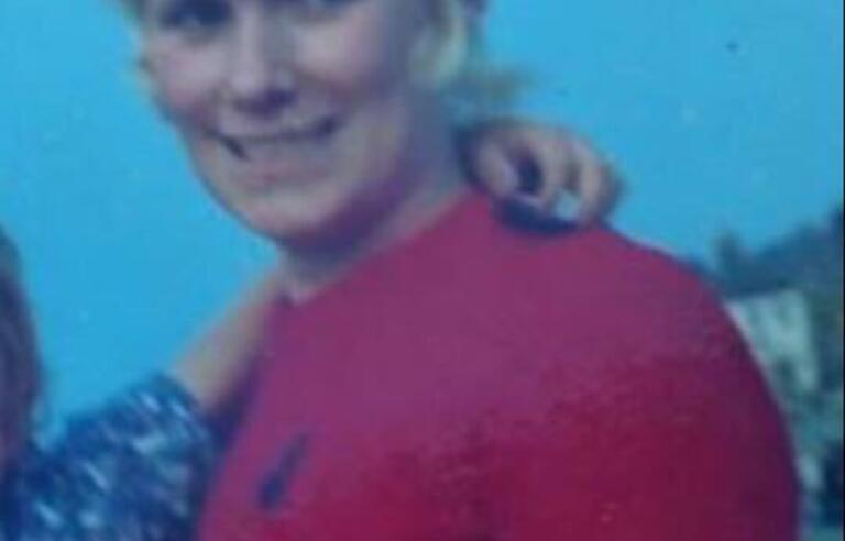 A woman with short blonde hair and a pink t-shirt