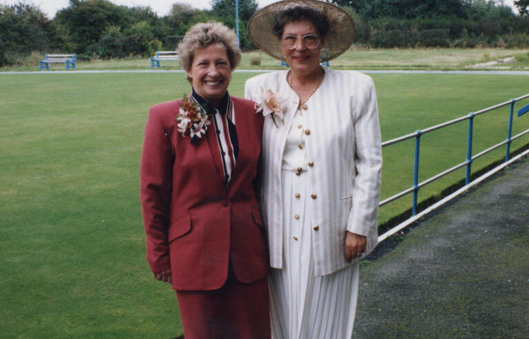 A woman with short blonde hair wearing a red suit stood next to another woman with a brown hair and white suit