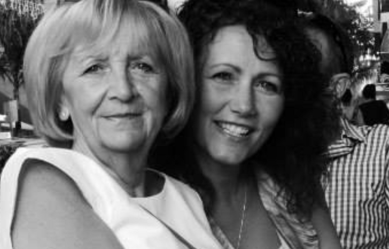A black and white photo of an older woman sat with a younger woman