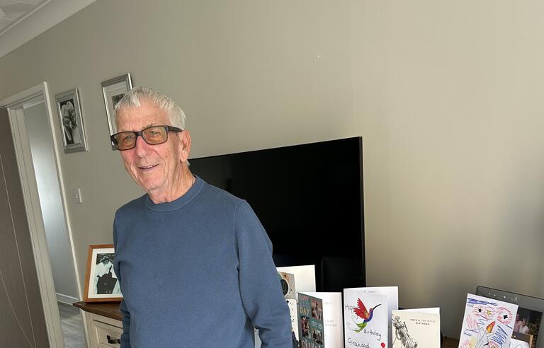 A man stood in front of a sideboard with cards on top