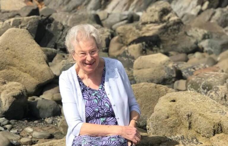 A woman sat on a rock on a beach