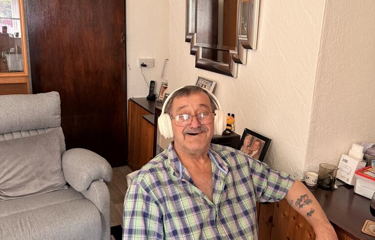 A smiling man wearing headphones sat in a chair