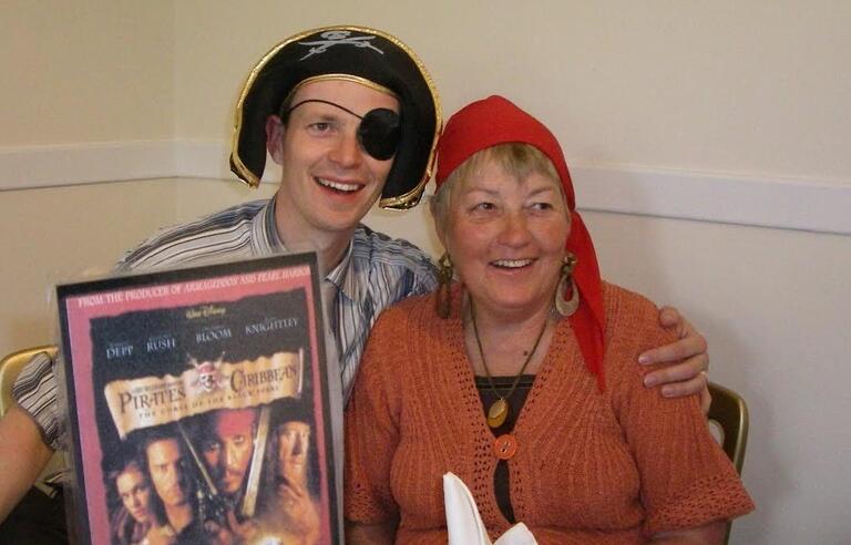 A man and woman dressed as pirates, smiling and hugging