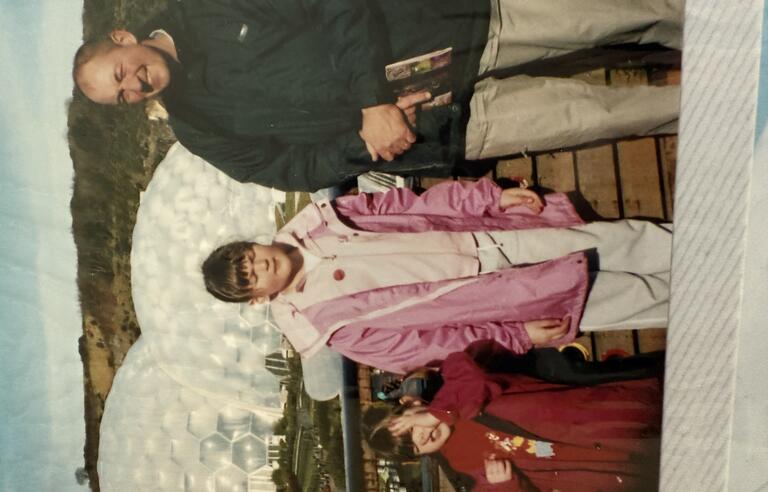 A film photo of a man, older girl and younger girl at the Eden Project. Two large domes are in the background